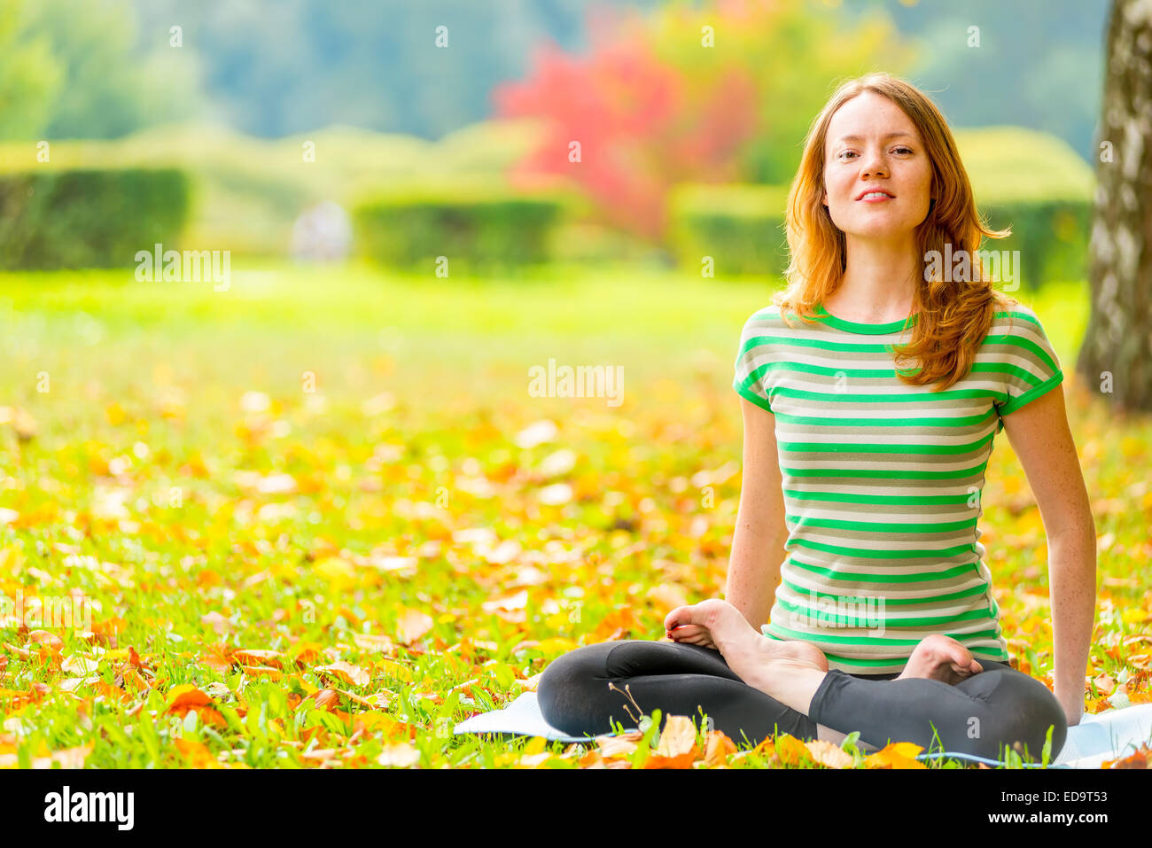 Barefoot fille rousse la pratique du yoga dans le parc en automne Banque D'Images