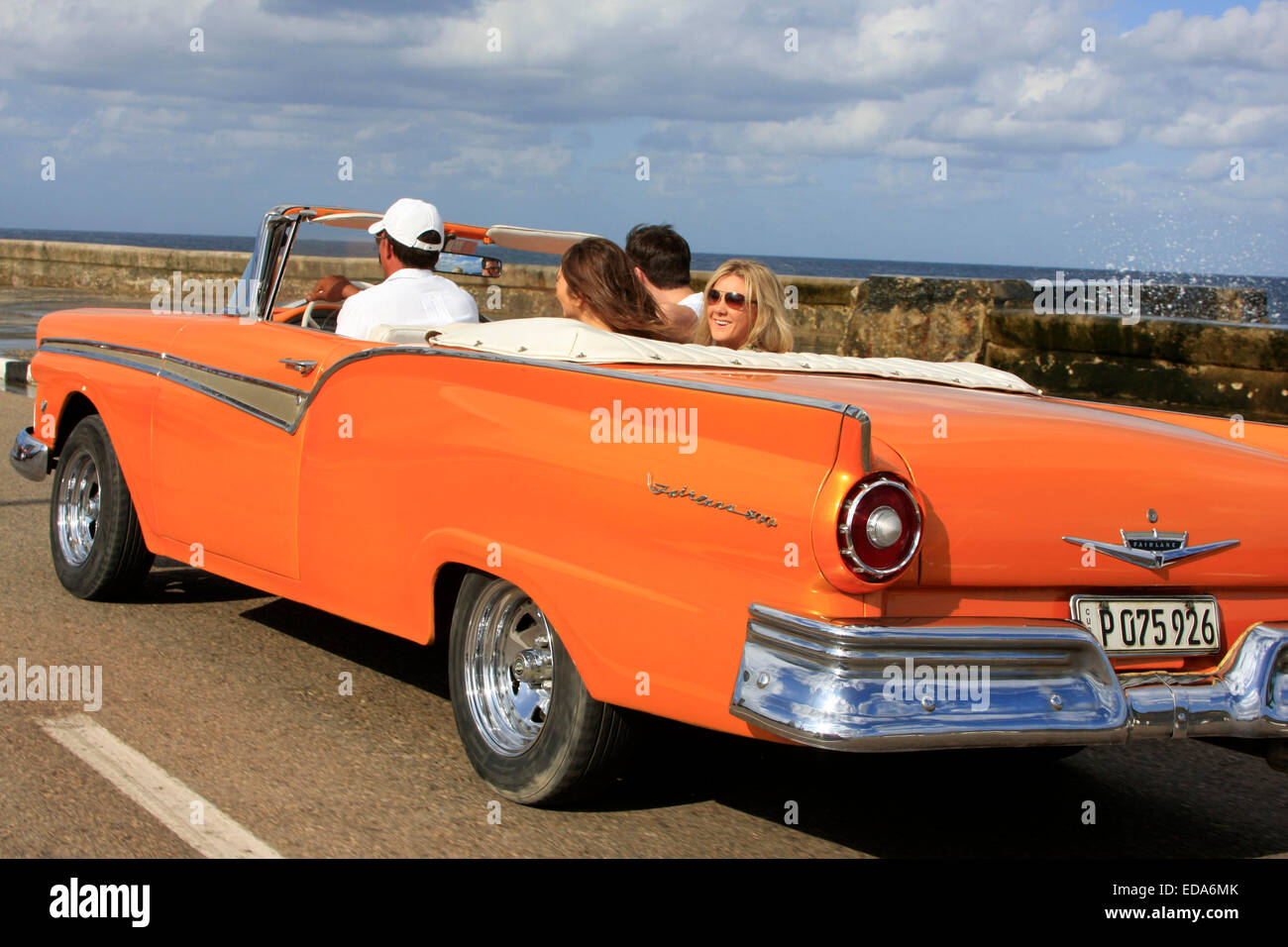 Les touristes voyageant dans une voiture décapotable vintage classique le long du Malecon de La Havane, Cuba Banque D'Images