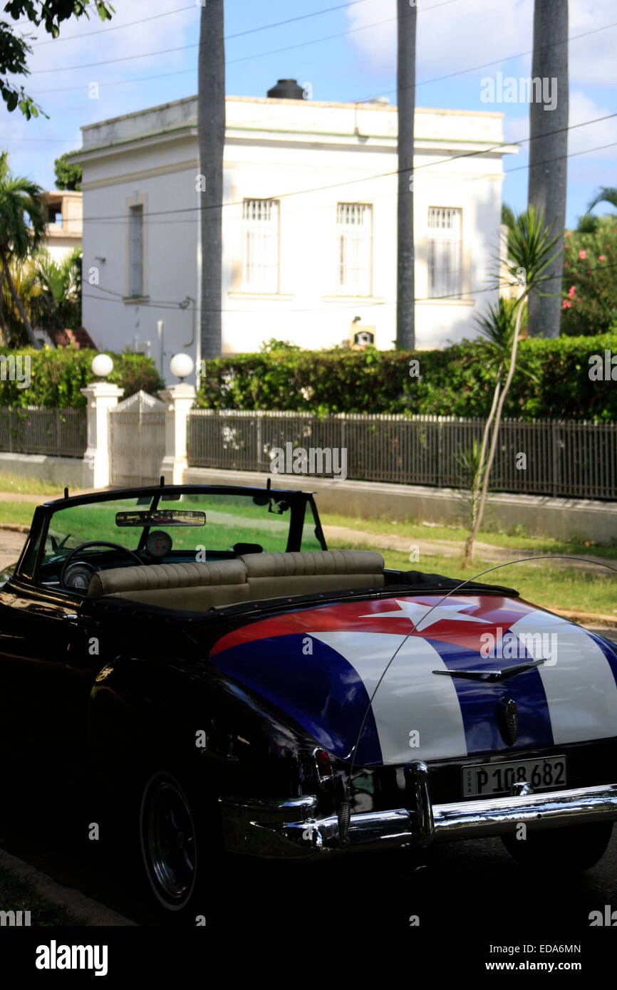 Une voiture américaine décapotable vintage avec le drapeau cubain peint sur elle - de La Havane, Cuba en face d'une grande villa Banque D'Images