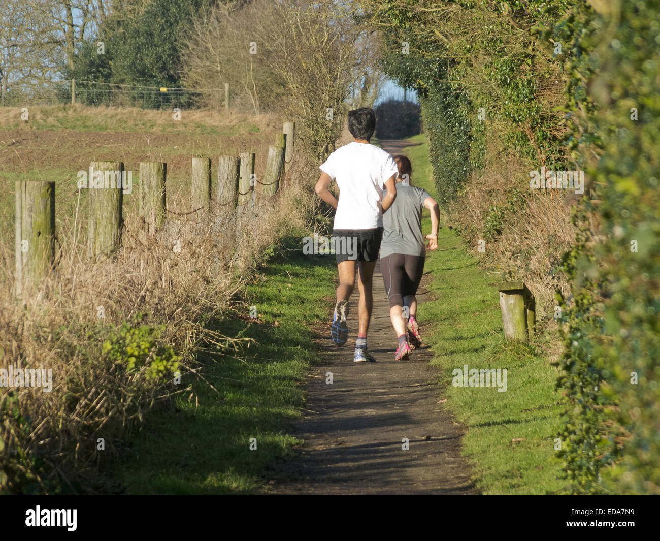 L'Homme asiatique et Caucasain femme tournant le long d'une fonction Bridleway, Cofton Hackett, Worcestershire, Angleterre, RU en hiver Banque D'Images