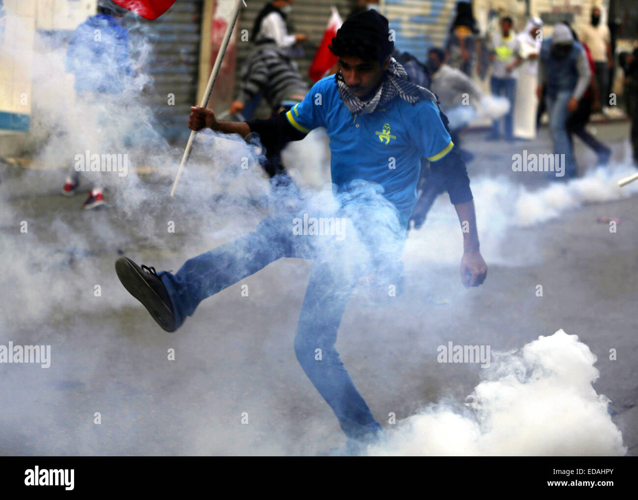 Manama, Bahreïn. 3 janvier, 2015. Un manifestant anti-gouvernement traite de gaz lacrymogènes tirés par les policiers anti-émeutes au cours de l'affrontement de Bilad al, près de presse Anatolie Manama, capitale de Bahreïn, 3 janvier 2015. Clash a éclaté dans de nombreuses régions de Bahreïn entre la police anti-émeutes et des manifestants qui réclament la libération de la principale opposition chiite Cheikh Ali Salman leader. © Hasan Jamali/Xinhua/Alamy Live News Banque D'Images