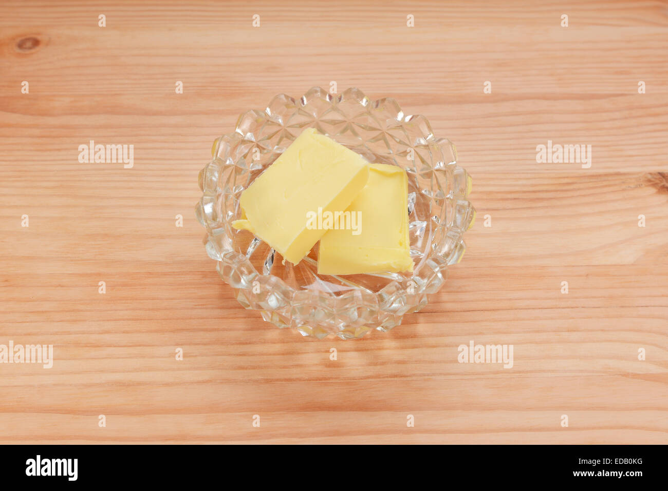 Deux pats de beurre dans un plat en verre sur une table en bois Banque D'Images