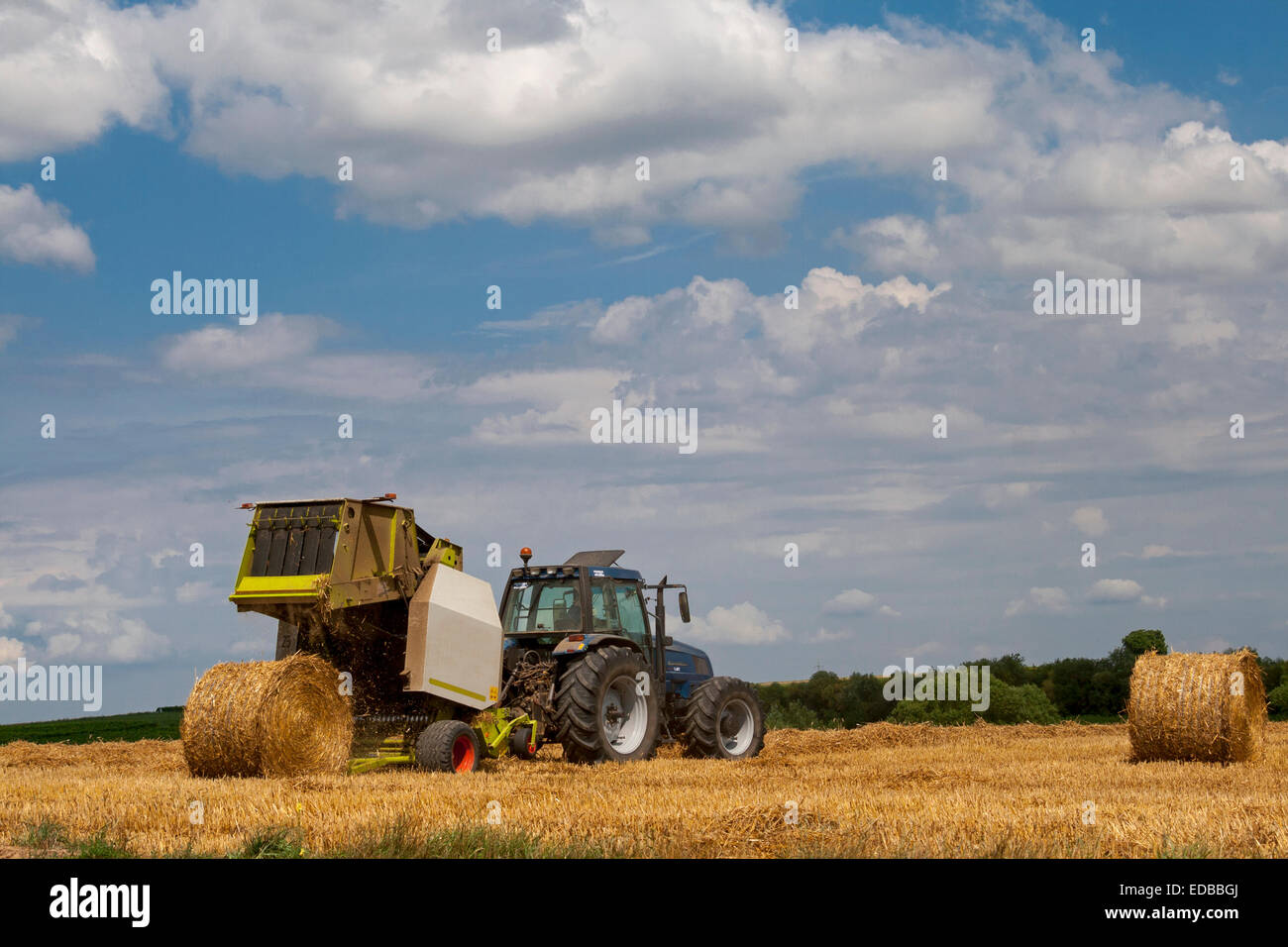 Agriculteur avec tracteur dans son domaine en bottes de paille