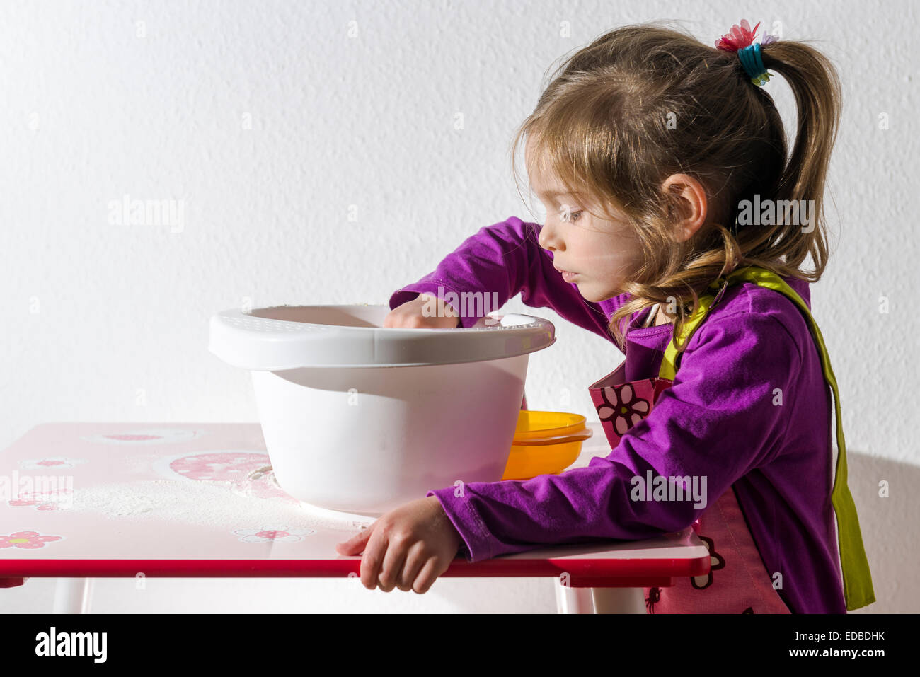 Fille, 3 ans, la cuisson, en remuant les ingrédients dans un bol blanc Banque D'Images