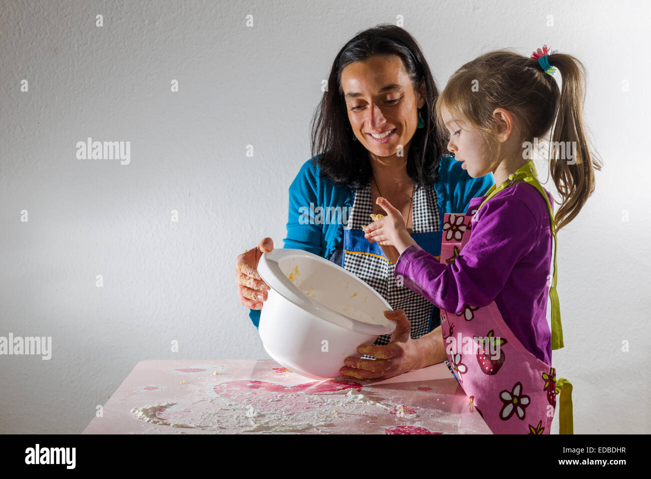 Fille, 3 ans, et sa mère, la cuisson, le mélange des ingrédients dans un bol blanc Banque D'Images