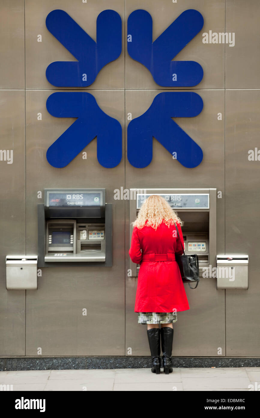 Une femme à l'aide d'un distributeur de billets de la RBS. Banque D'Images