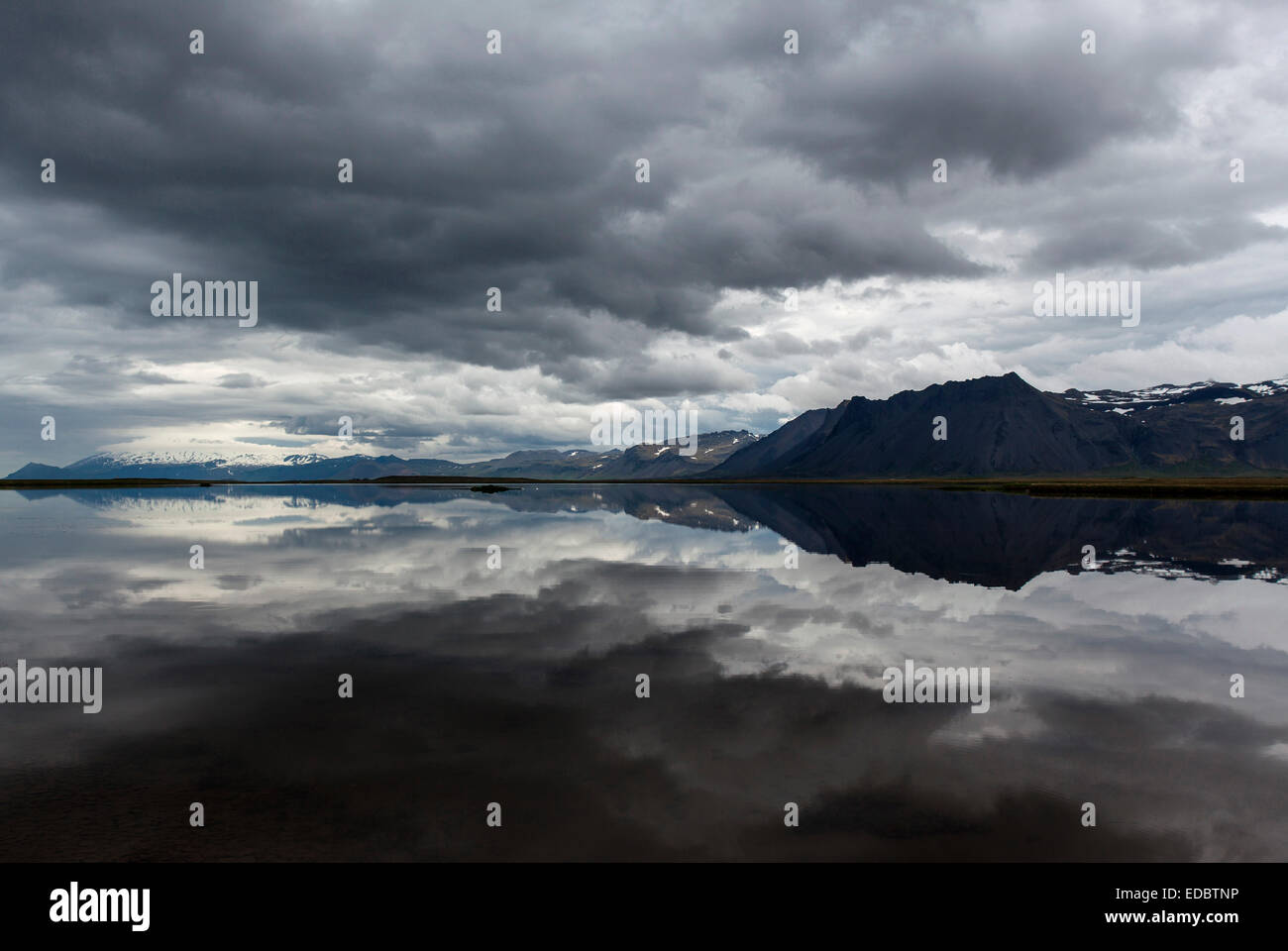 Lac, montagne à theback, des nuages sombres se reflètent dans l'eau, à proximité de Gardar, péninsule de Snæfellsnes, l'Islande Banque D'Images