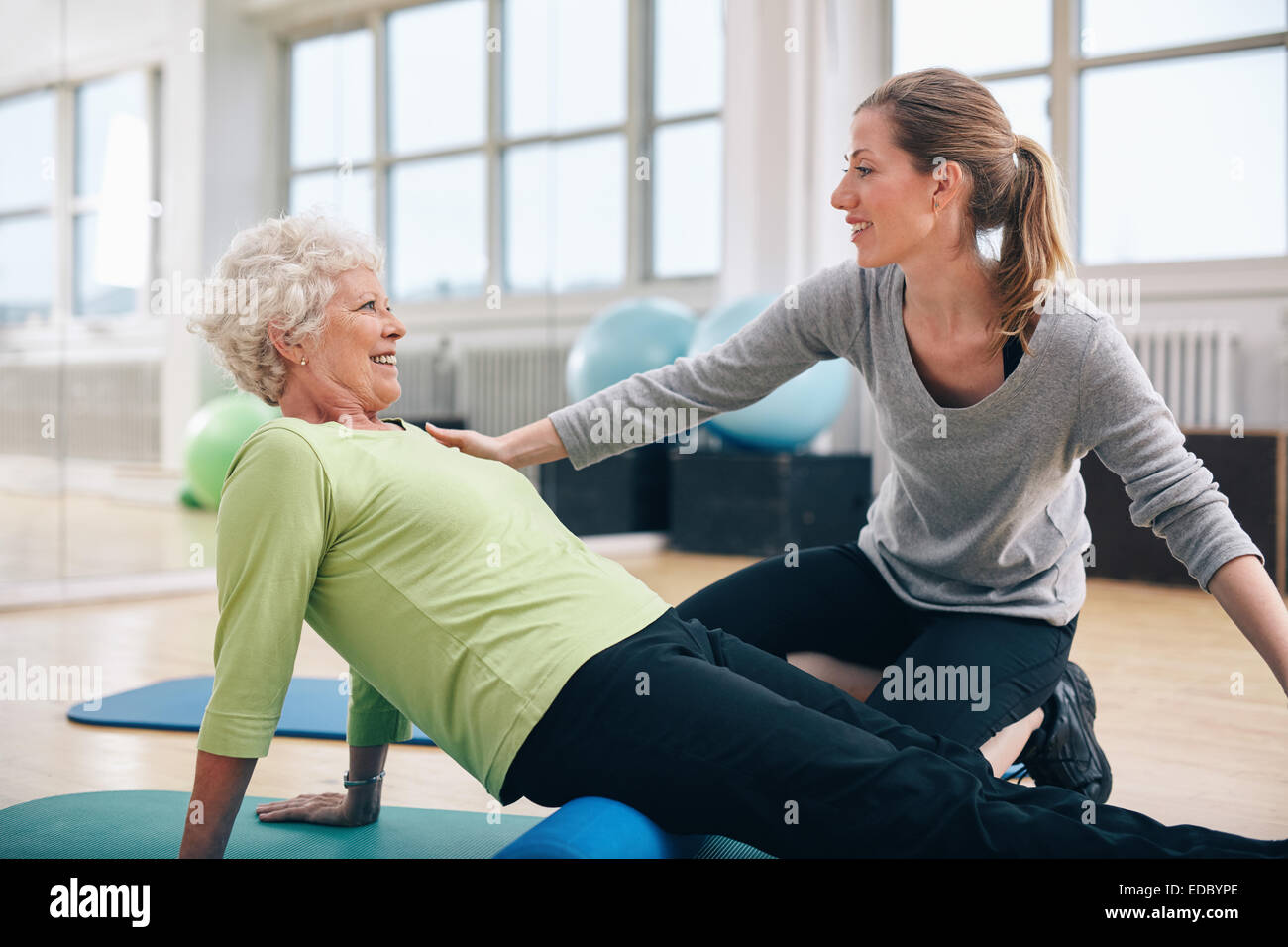 Physiothérapeute travaille avec un aîné femme à rehab. Femme trainer helping senior woman doing exercise sur rouleau en mousse à Gy Banque D'Images