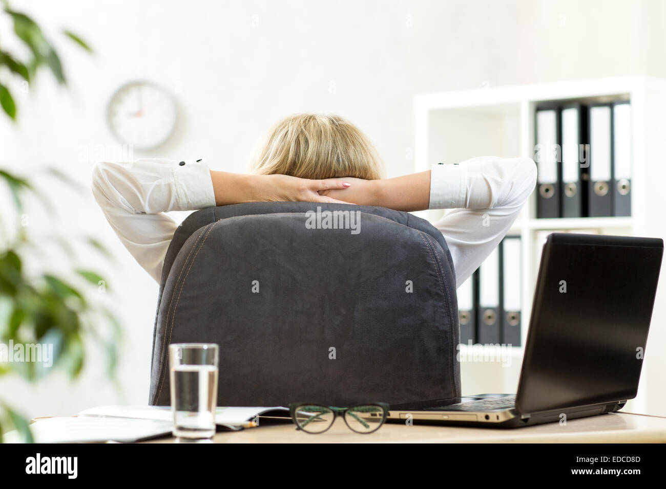 Office assis en chaise avec les mains derrière le cou Banque D'Images