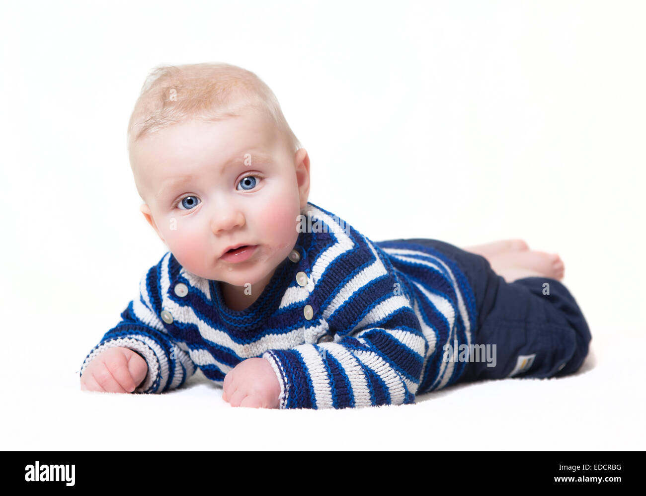 Bébé avec les yeux bleus couché looking at camera, fond blanc Banque D'Images