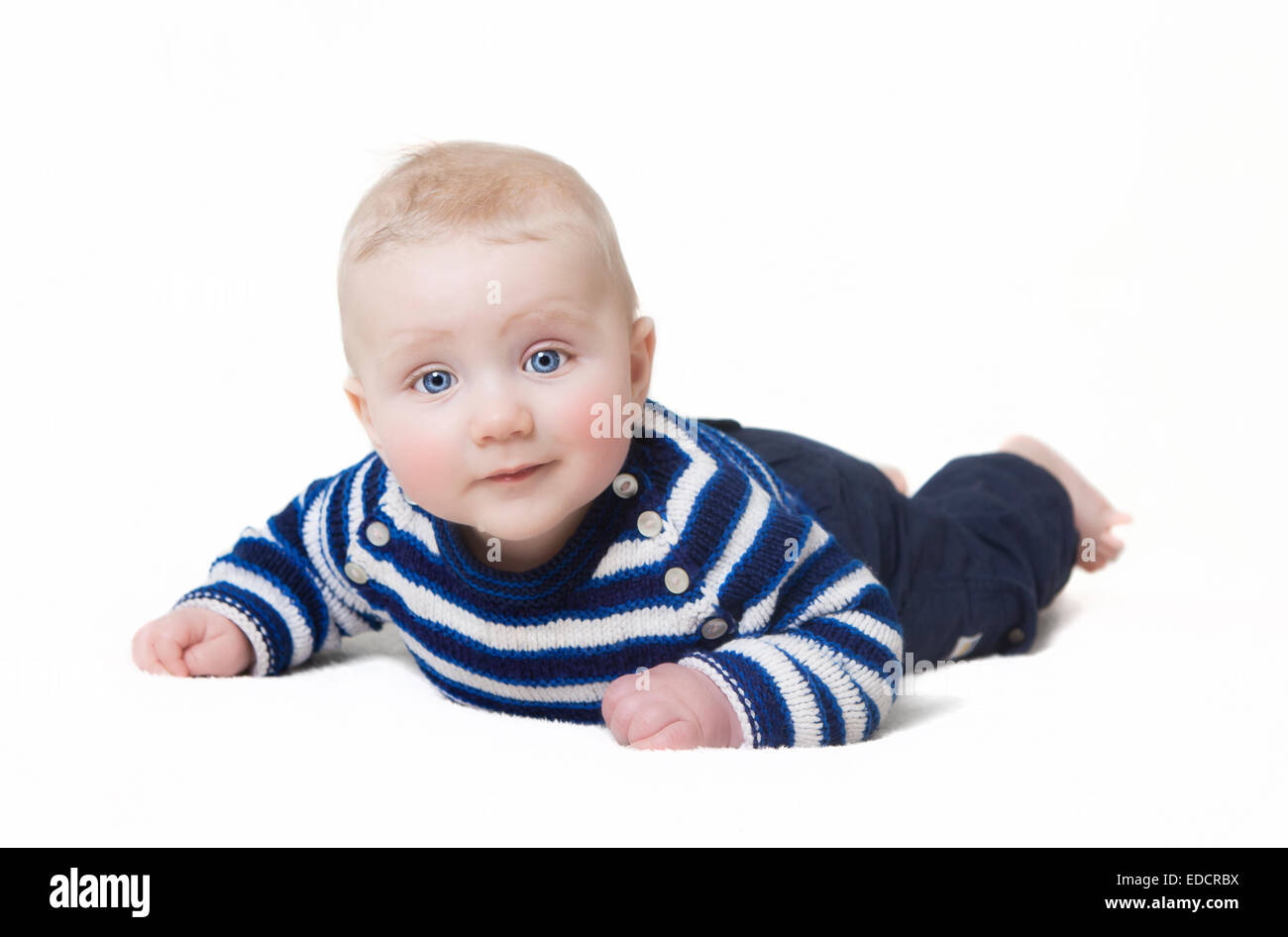 Bébé avec les yeux bleus couché looking at camera, fond blanc Banque D'Images