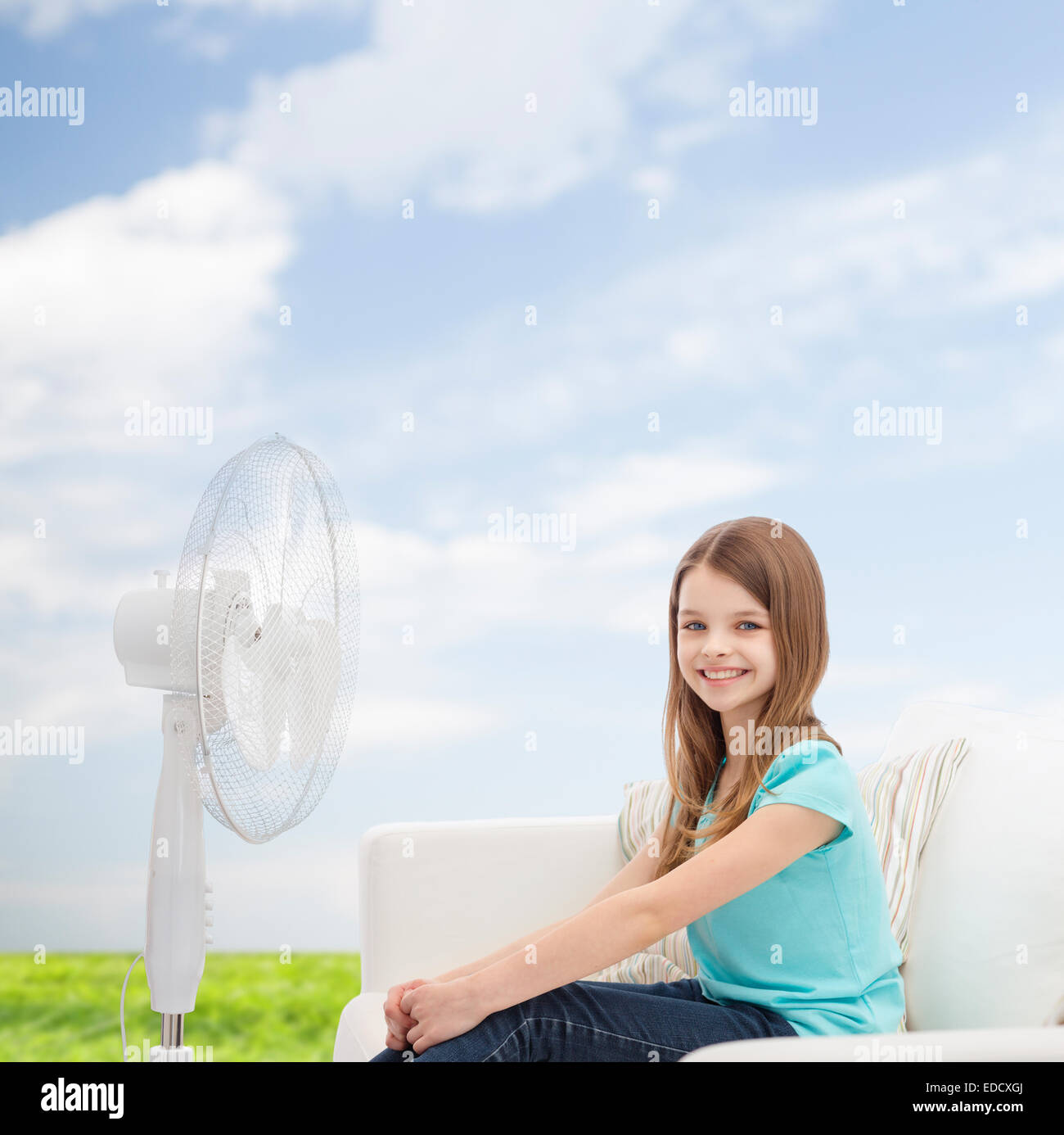 Smiling little girl avec grand fan à la maison Banque D'Images