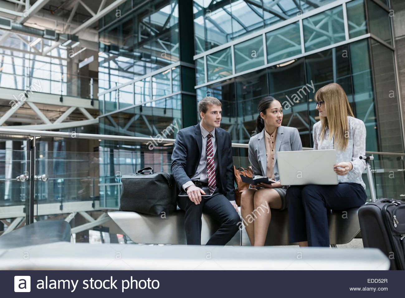 Business people using laptop in airport atrium Banque D'Images