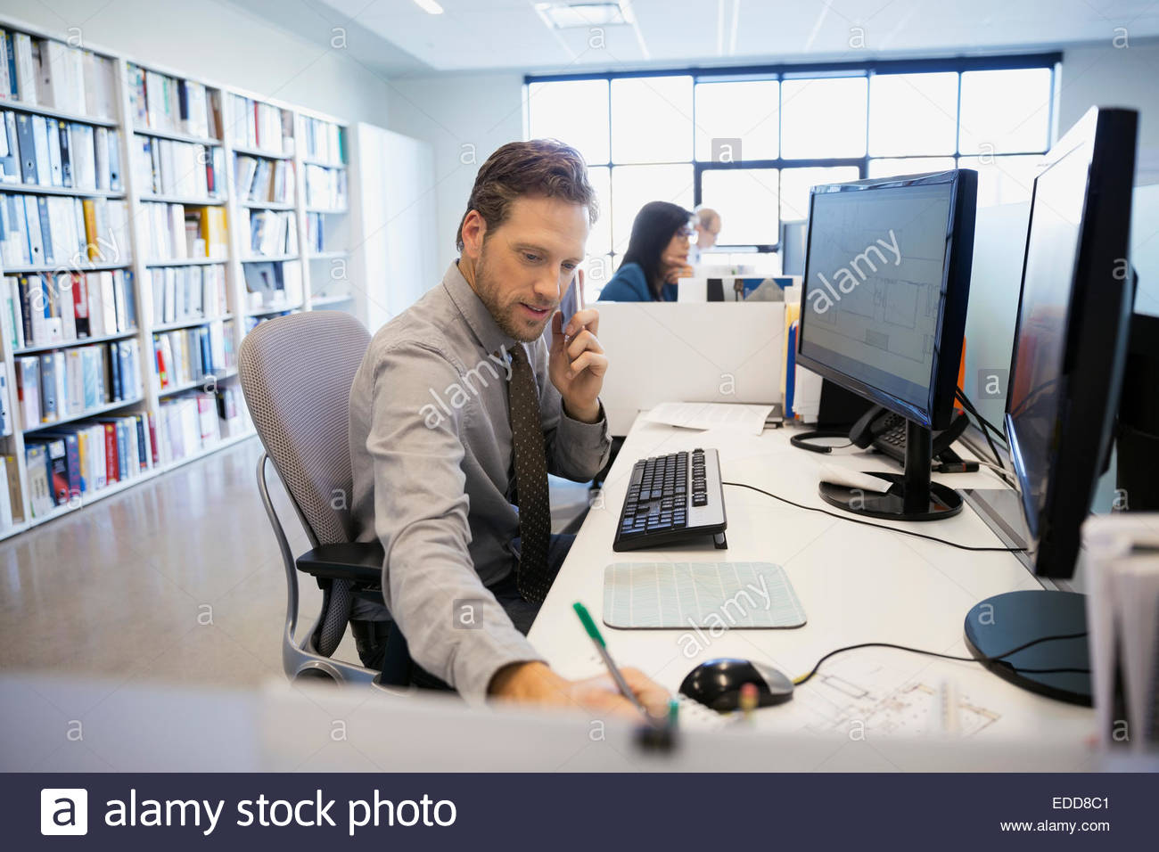 Businessman talking on cell phone at office desk Banque D'Images