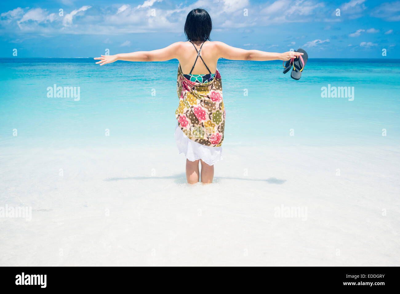 Maldives, Ari Atoll, jeune femme debout dans l'eau à front de mer Banque D'Images