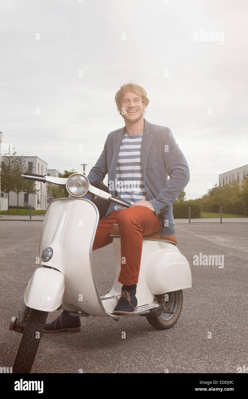 Homme heureux assis sur son scooter Banque D'Images