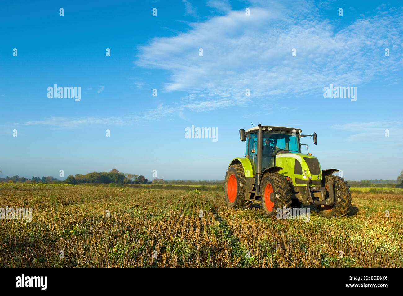 Un tracteur dans un champ de chaume dans le Gloucestershire. Banque D'Images