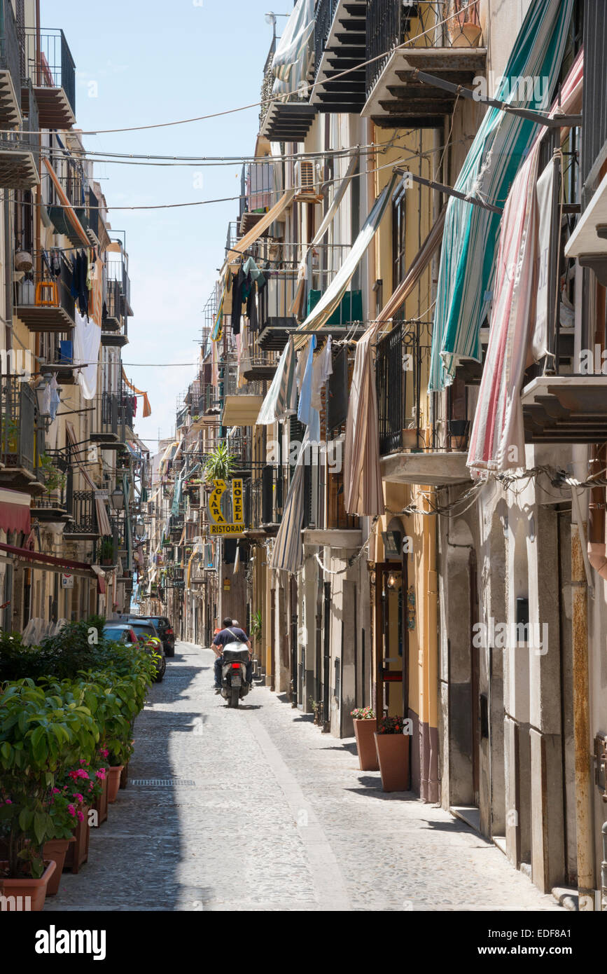 Une rue étroite à Cefalu Sicile Italie avec un scooter de les enfourcher. Lave et les auvents accrocher depuis les balcons des bâtiments Banque D'Images