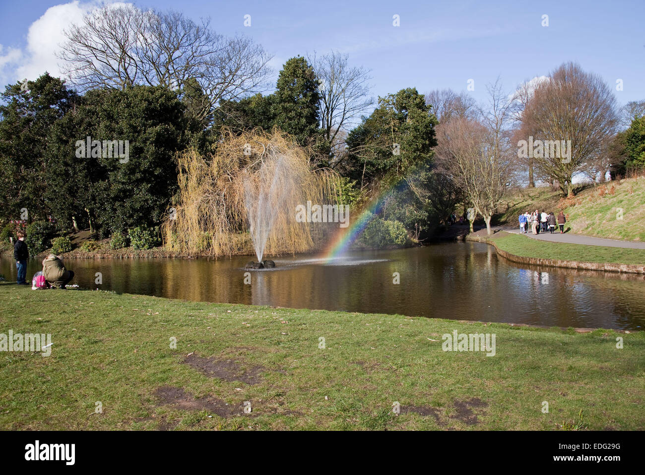 Dispositif de l'eau dans un parc public au début du printemps, avec la lumière du soleil sur la capture à un angle de pulvérisation de manière à provoquer un arc-en-ciel Banque D'Images