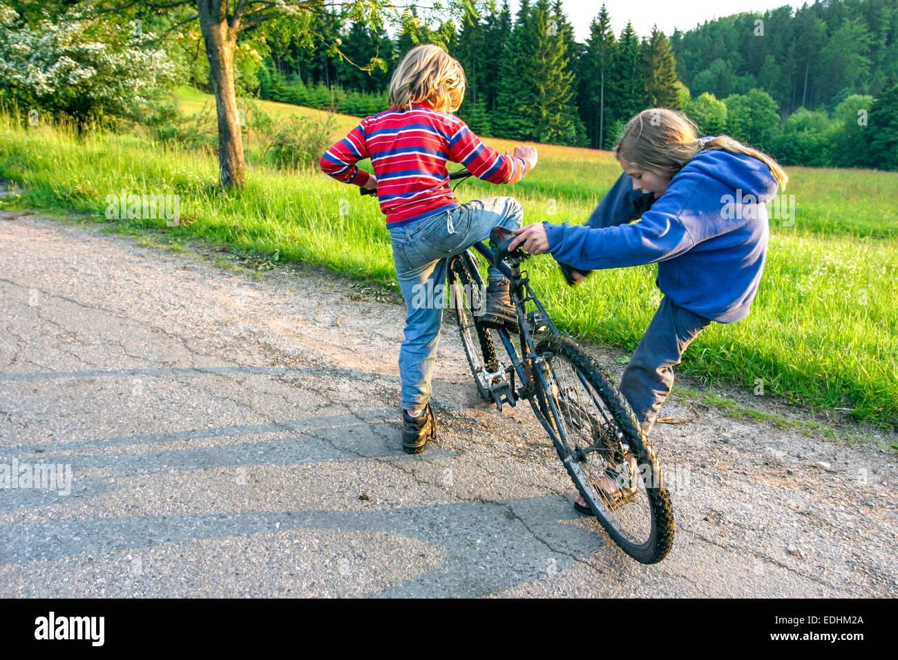 Enfants et un vélo sur la route de campagne, enfants vélo enfants, route rurale de bord de route garçon et fille Banque D'Images