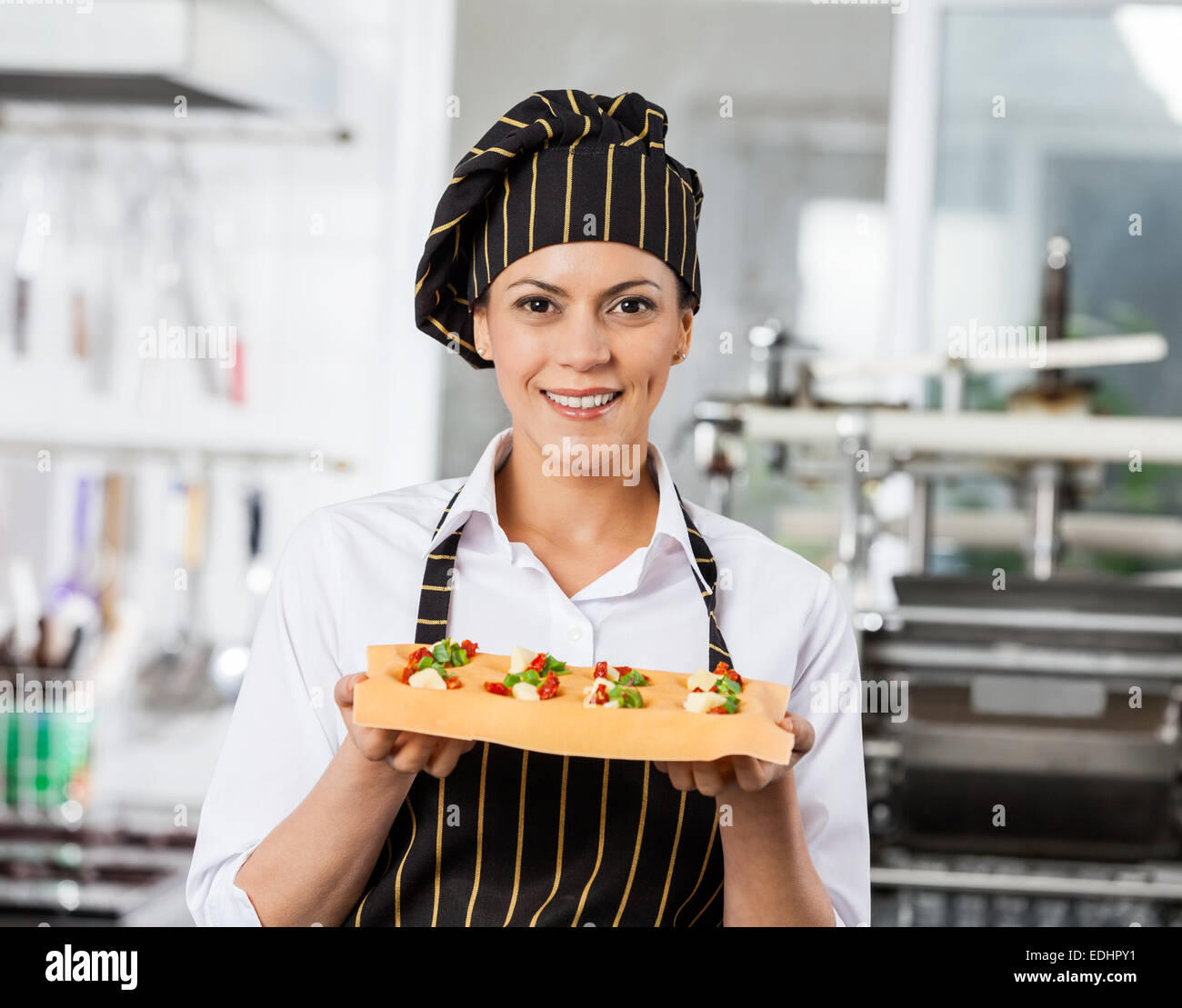 Portrait of happy chef holding tray with feuille de pâtes farcies Banque D'Images