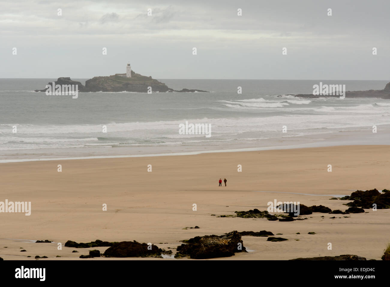 Les gens qui marchent sur la plage sur Gwithian jour d'automne froid avec Godrevy lighthouse dans la distance à Gwithian, Cornwall, Angleterre Banque D'Images