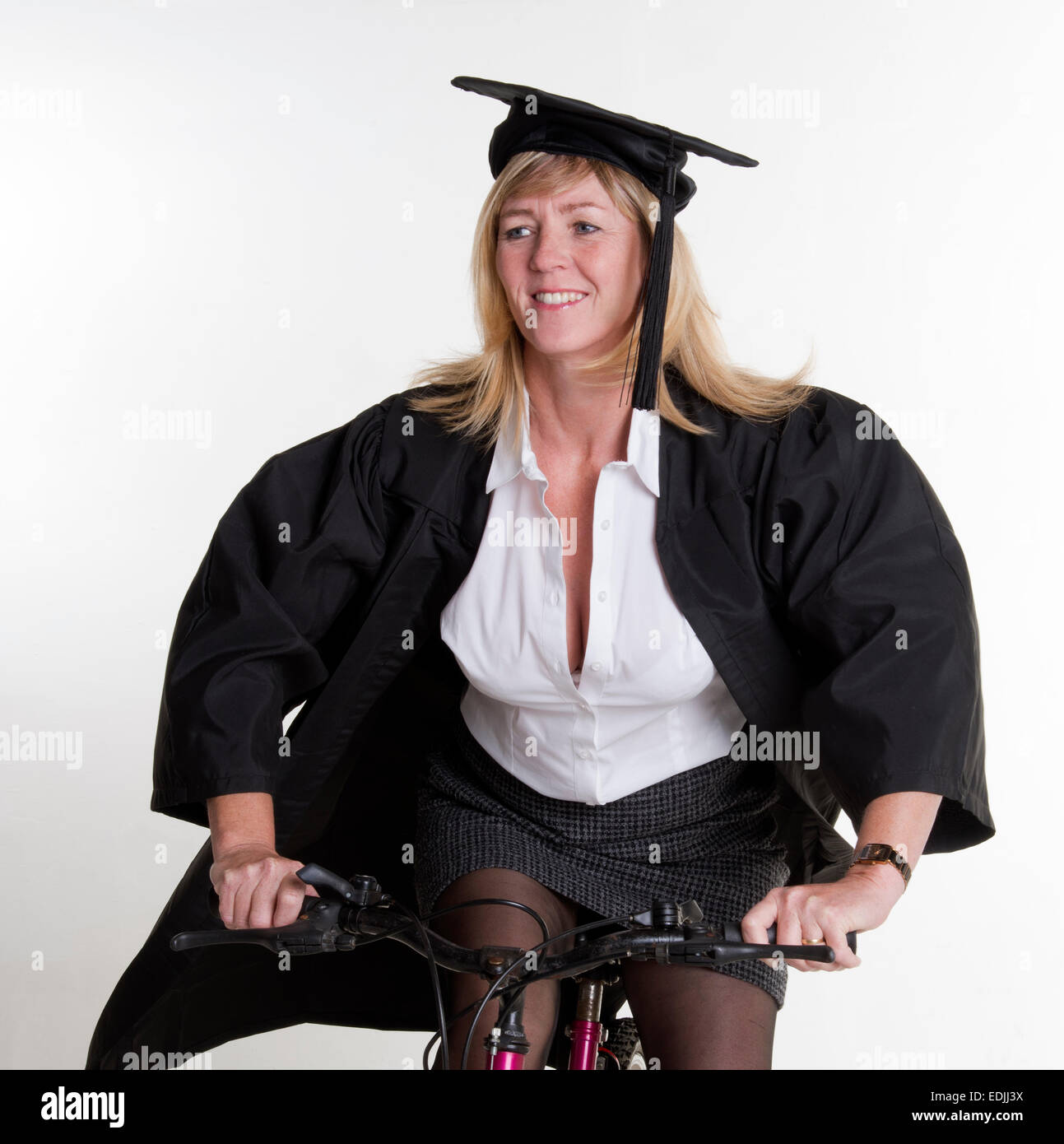 Femelle adulte étudiant Université de la bicyclette wearing cap and gown Banque D'Images