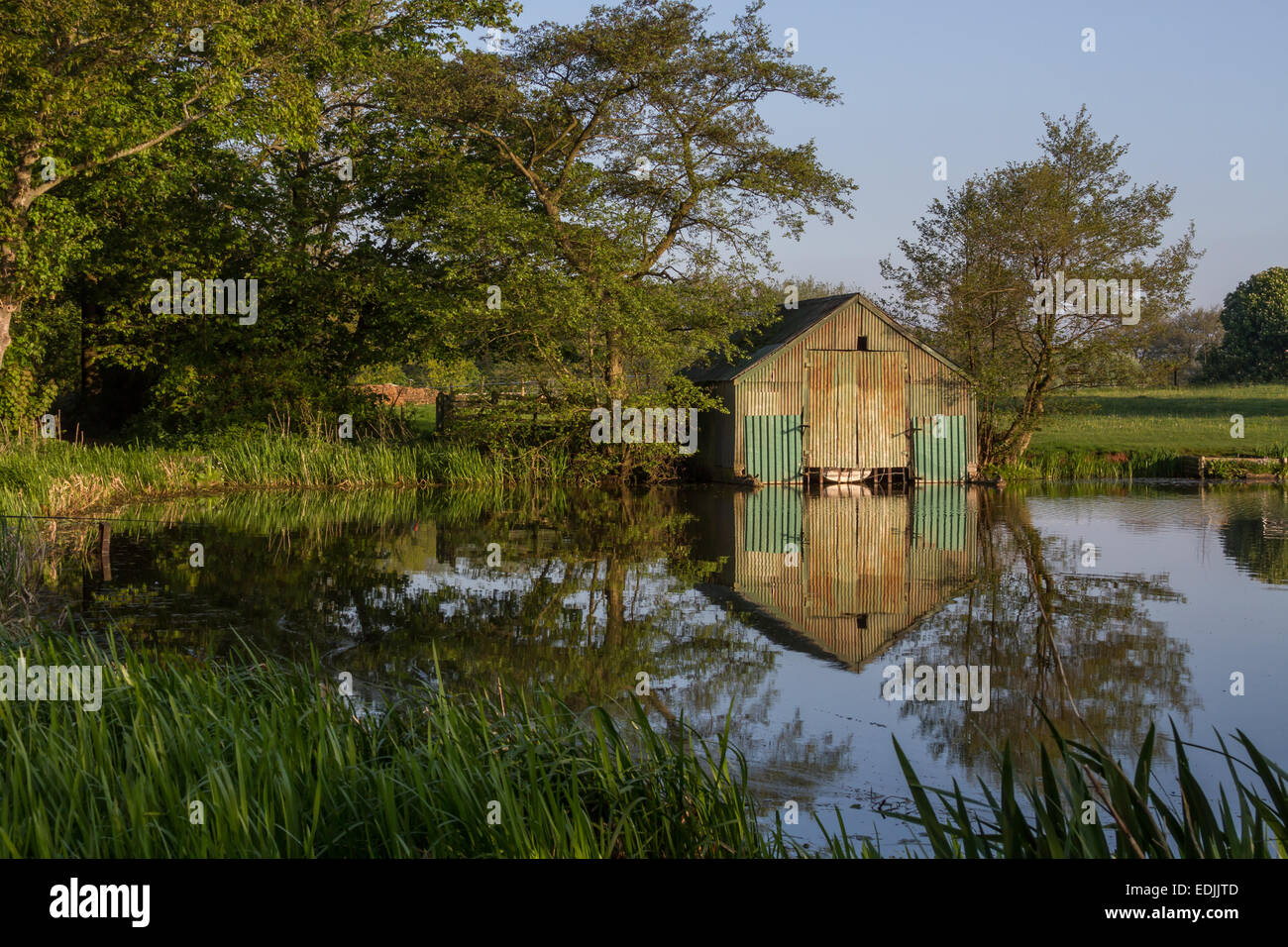 Ancien hangar à bateaux sur un lac avec reflets dans l'eau Banque D'Images