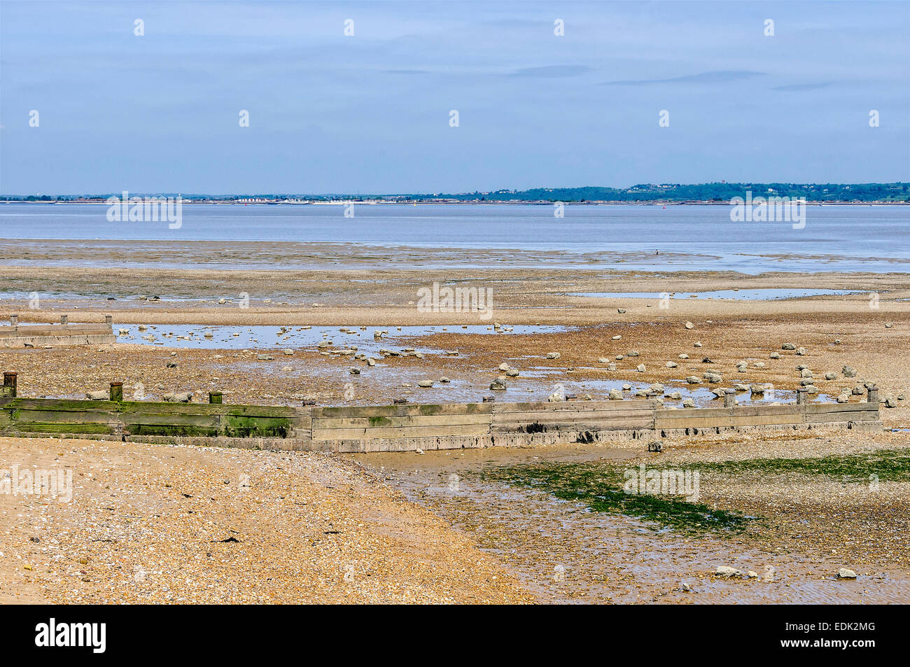 Un cadre tranquille Tamise passe par une plage de galets d'une seule banque et bâtiments industriels et domestiques sur l'autre rive Banque D'Images