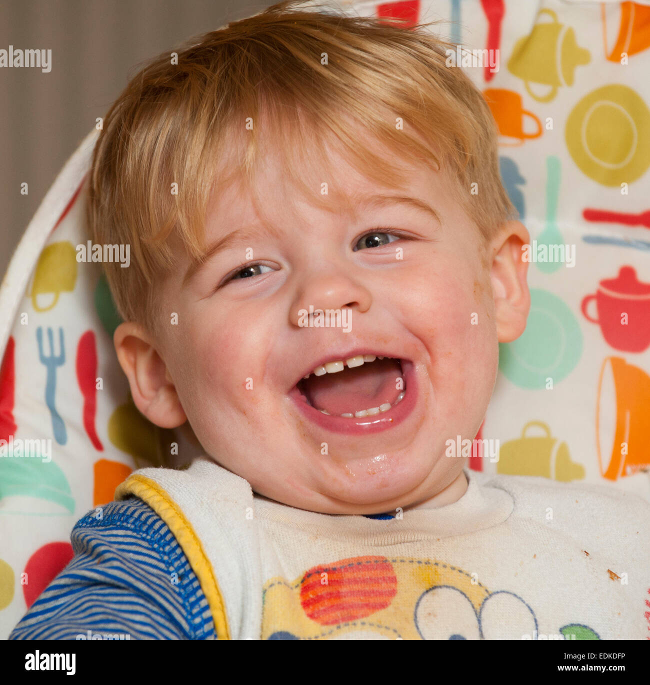 Un enfant de deux ans rire dans une chaise haute. Banque D'Images