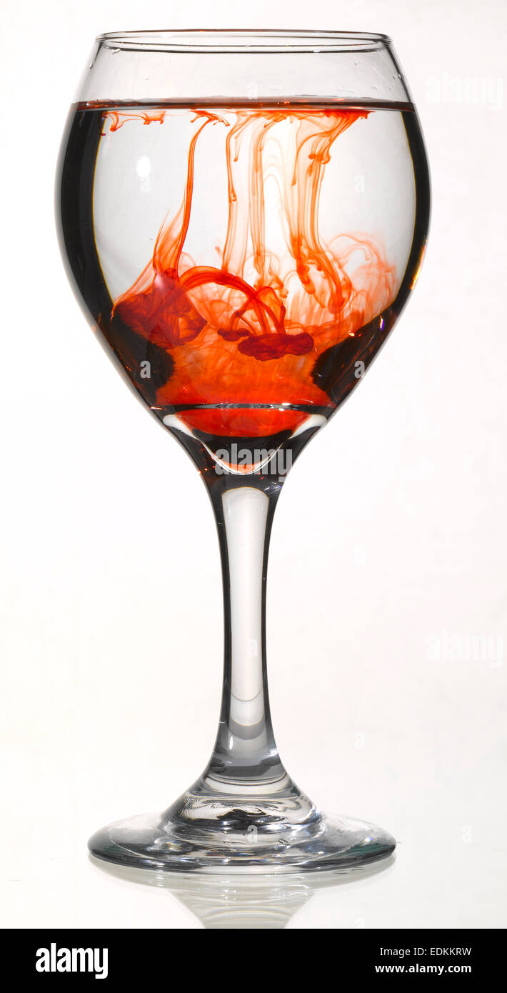 Colorant alimentaire rouge dans le verre de vin Banque D'Images