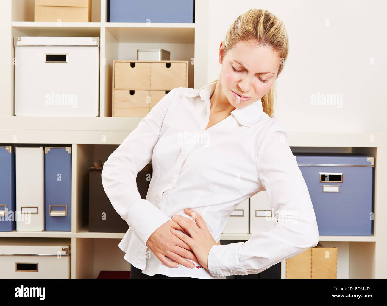 Business Woman in office avec les maux de dos debout et tenant sa hanche Banque D'Images
