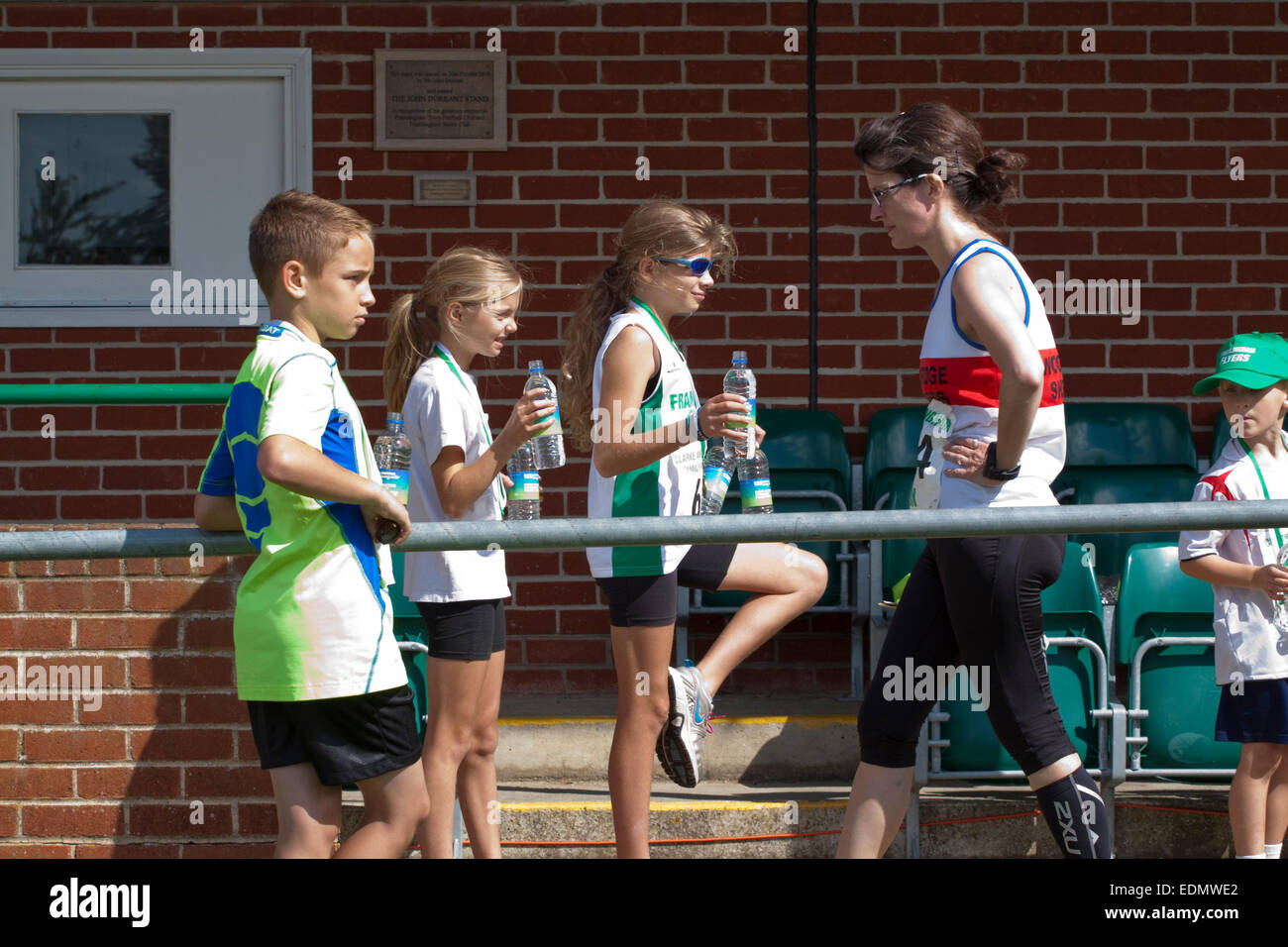 Les enfants offrent de l'eau embouteillée aux coureurs qui viennent juste de terminer une course sur route de 10k Banque D'Images