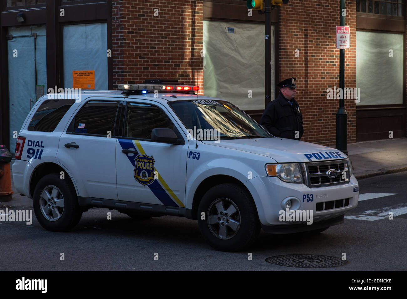 Un agent de police de Philadelphie en uniforme se trouve à côté d'un véhicule de police. Banque D'Images