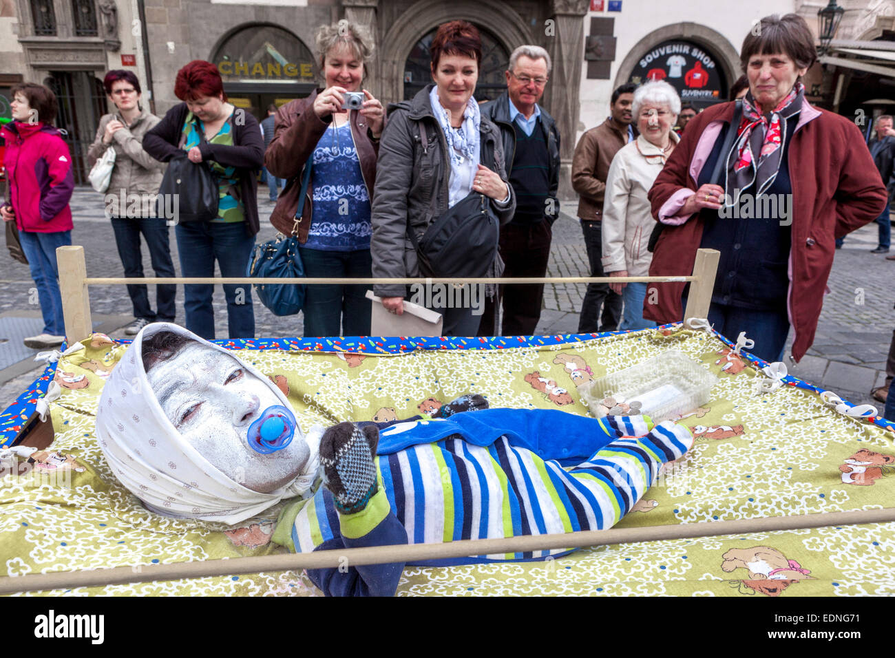 Un artiste de rue habillé comme un bébé dans un berceau, les gens de Prague touristes place de la Vieille ville de Prague buckers Banque D'Images