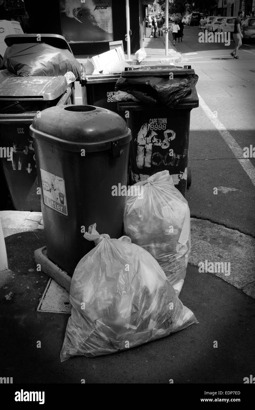 Des sacs poubelle et refuser wheelie bins sur trottoir en street dans le centre-ville du Cap . (Noir et blanc) Banque D'Images