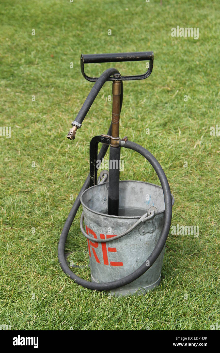 Une pompe dans un étrier Vintage Metal Fire Bucket. Banque D'Images