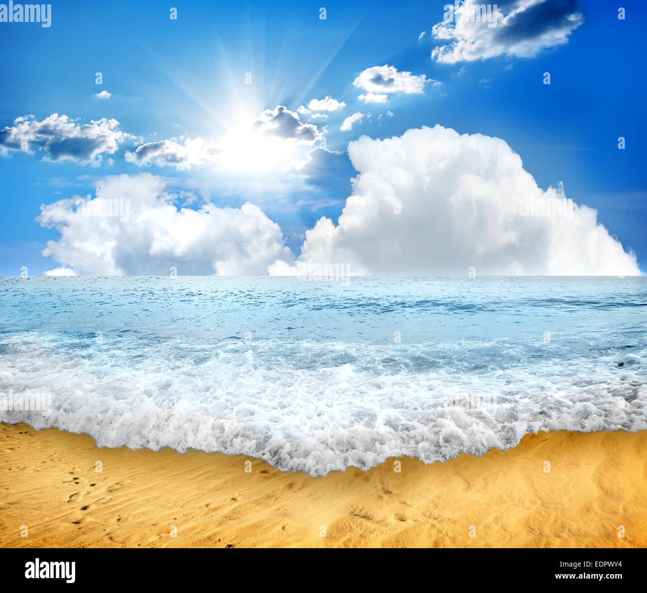 Mer vague mousseuse et plage de sable à la lumière du soleil Banque D'Images