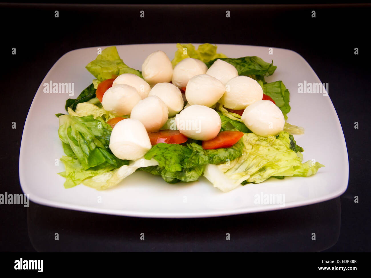 Salade avec tomates et mozzarella sur un fond noir Banque D'Images