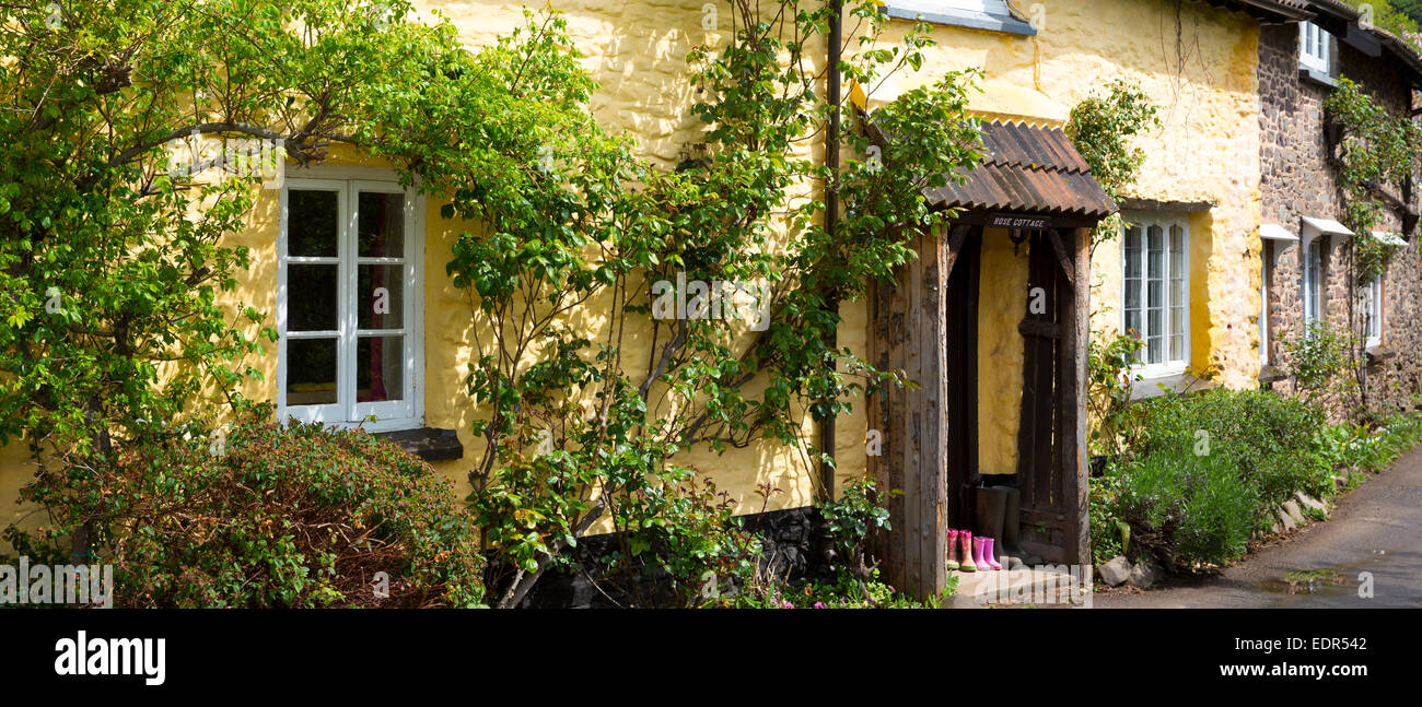 Bottes Wellington à l'avant porte de quaint cottage traditionnel en Bossington dans Exmoor, Somerset, Royaume-Uni Banque D'Images