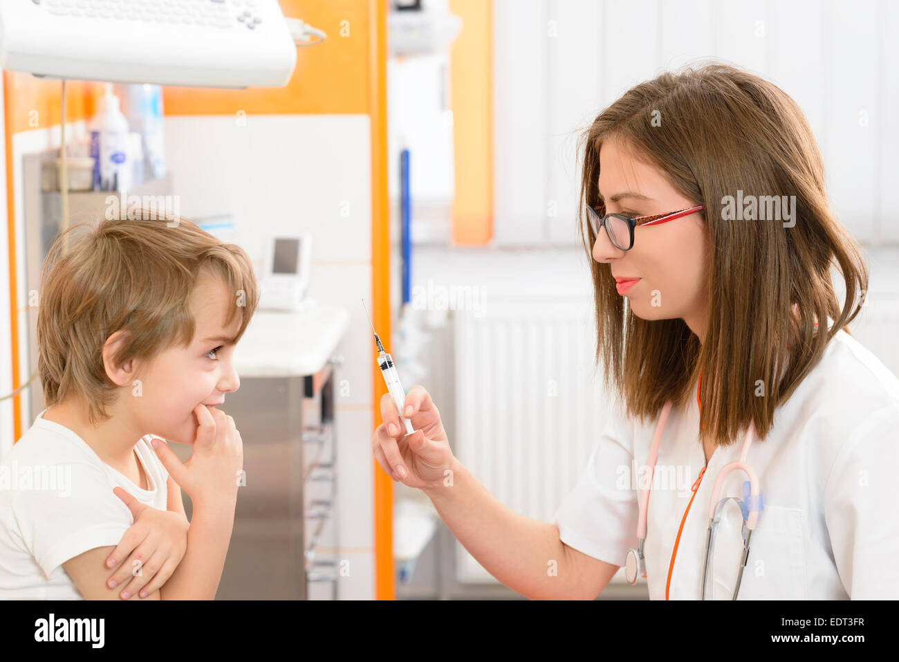 Un mignon petit garçon à la recherche d'un drôle en seringue dans un cabinet médical Banque D'Images