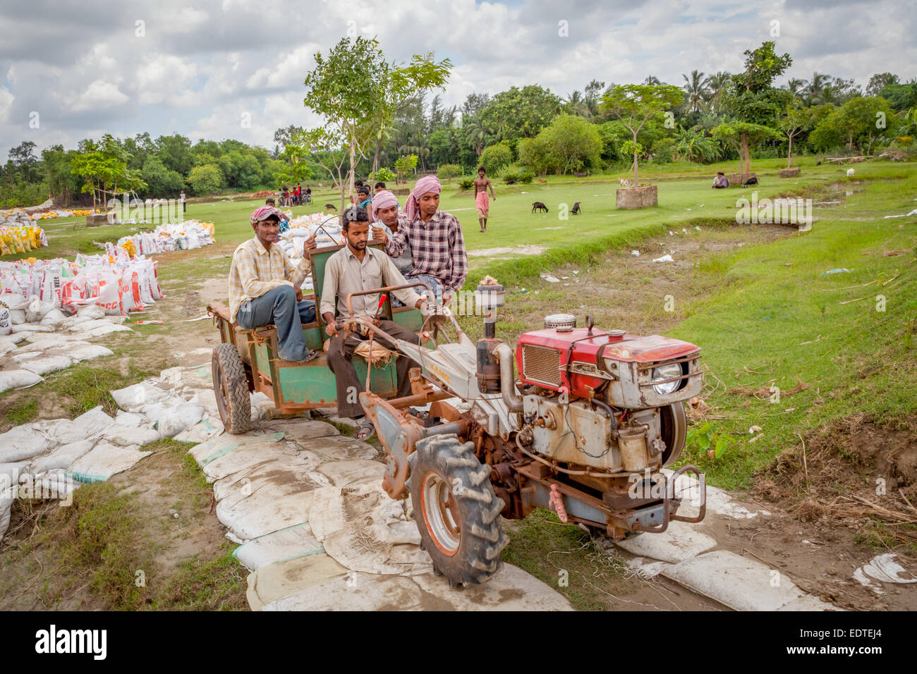 Travailleurs de la construction à bord d'un tracteur équipé d'un chariot lors d'un projet de contrôle de l'érosion fluviale sur la rive du fleuve Rupnarayan à Tamluk, en Inde. Banque D'Images