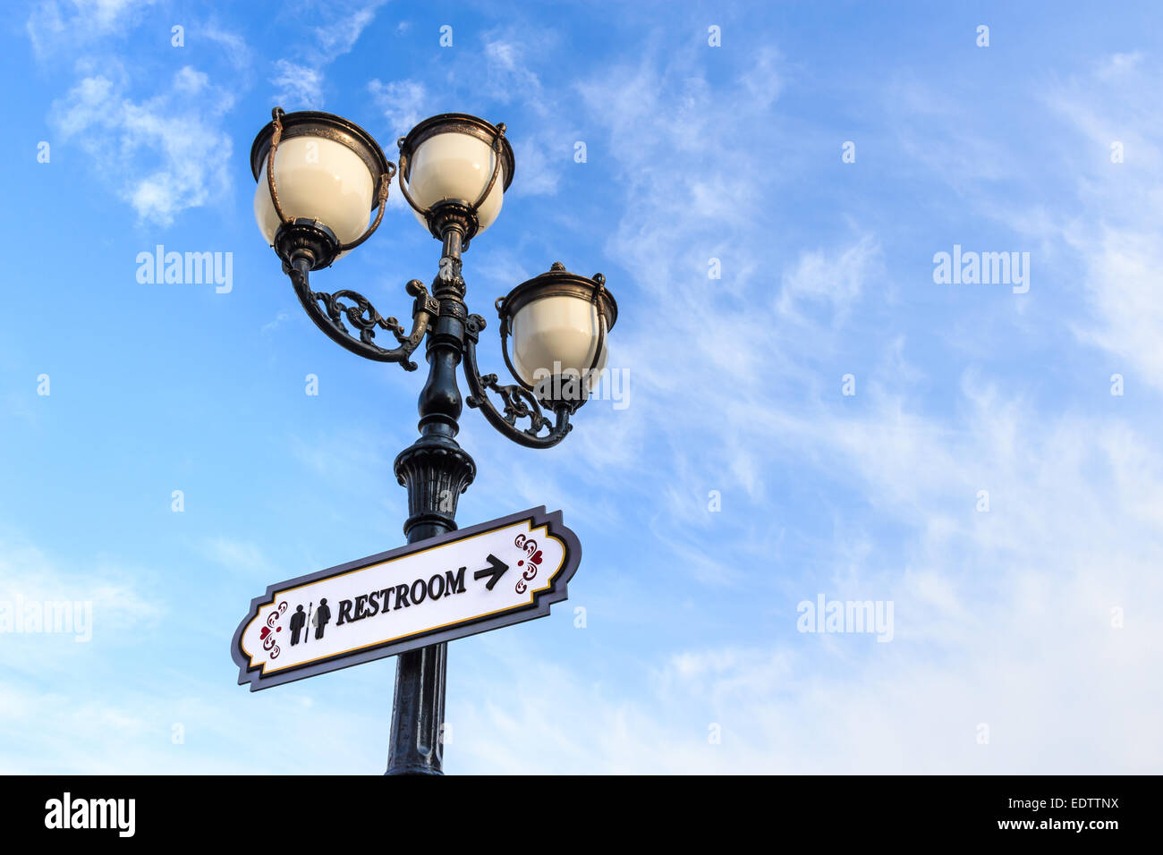 Lampe de rue et panneau à texte(WC) sur fond de ciel nuageux Banque D'Images