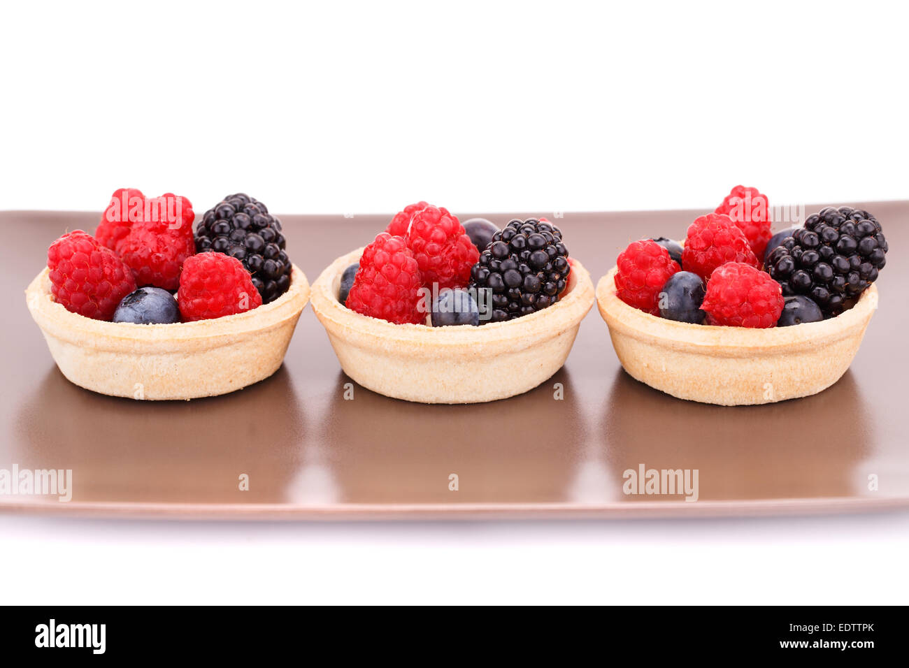 Tartelettes aux fruits frais mûrs dans sur la plaque brune. Banque D'Images