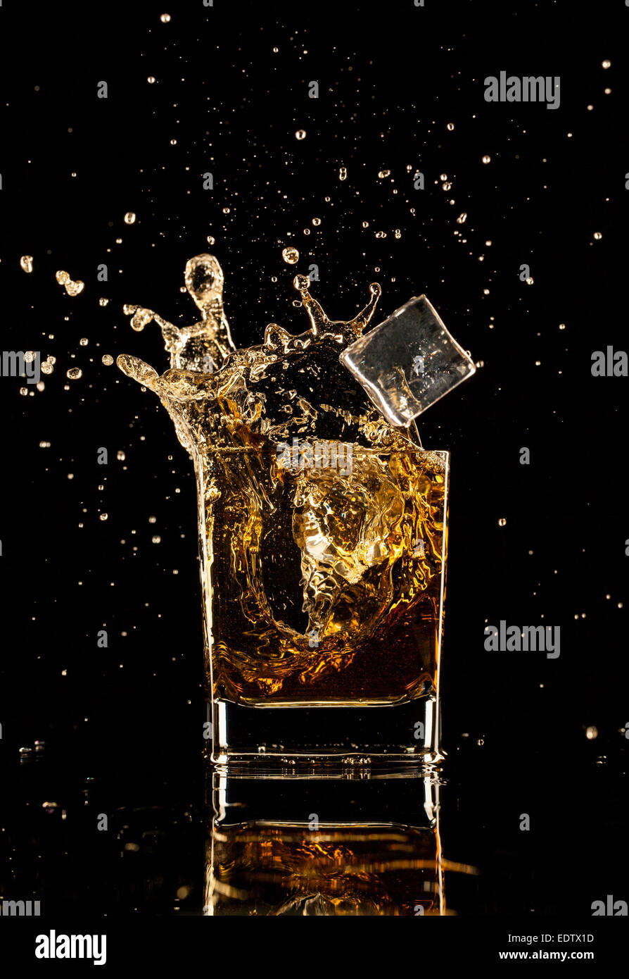 Shot de whiskey isolé avec splash sur fond noir Banque D'Images