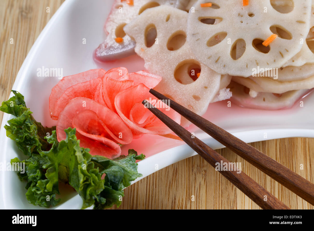 Close up image horizontale de l'eau, le radis chinois lotus blanc dans un plat, avec des baguettes de bambou naturel contexte Banque D'Images