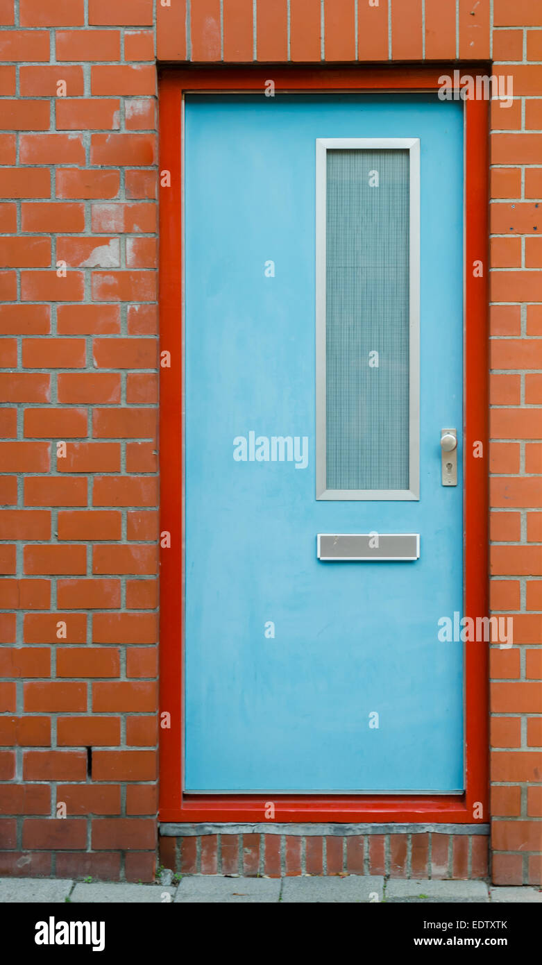 Une porte bleu clair contraste contre un cadre orange et brique en terre cuite Banque D'Images