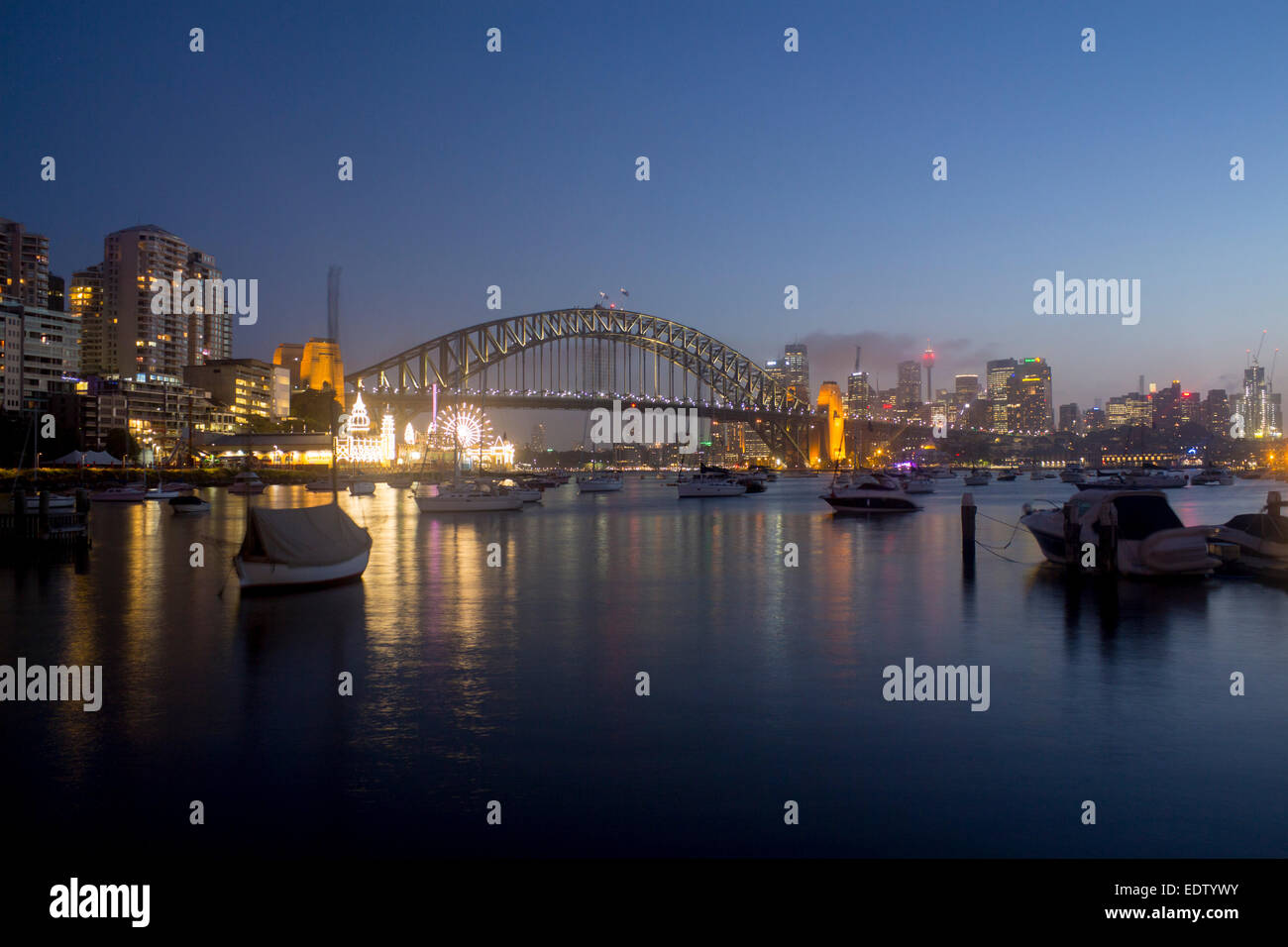 Lavender Bay bateaux en vue sur le port de Sydney Harbour Bridge CBD skyline skyscrapers et Luna Park la nuit Sydney NSW Australie Banque D'Images
