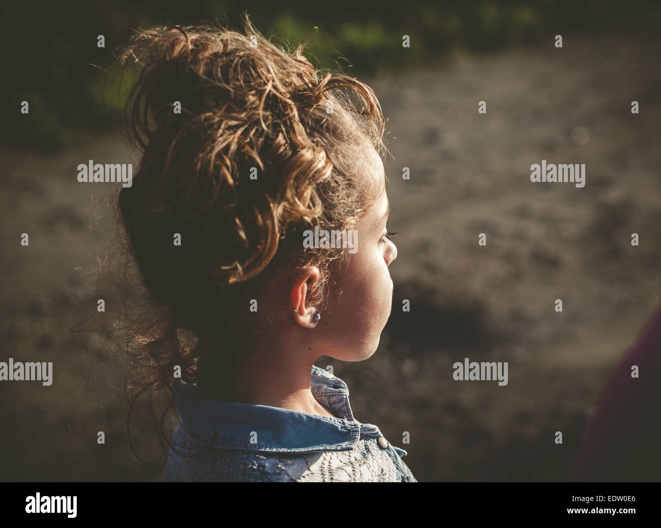 Petite fille lookin de côté à l'extérieur dans une journée ensoleillée Banque D'Images