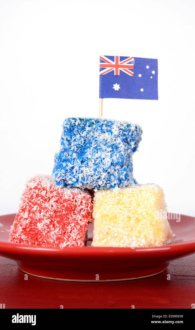 Heureux l'Australie jour rouge, blanc et bleu lamingtons cuisine de fête sur table en bois rouge contre l'arrière-plan blanc. Gros plan vertical. Banque D'Images